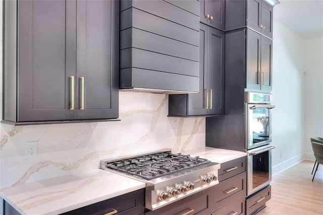 3960 Stock Rd, Monroe, GA 30656 - kitchen featuring stainless steel appliances, ventilation hood, decorative backsplash, light stone countertops, and light wood finished floors