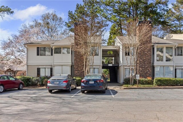 view of property with uncovered parking and stairs