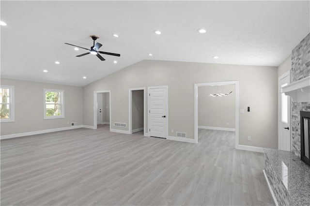 unfurnished living room featuring ceiling fan, a fireplace, vaulted ceiling, and light wood-type flooring