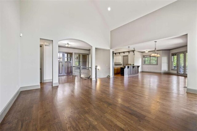 unfurnished living room with dark hardwood / wood-style flooring, high vaulted ceiling, and french doors