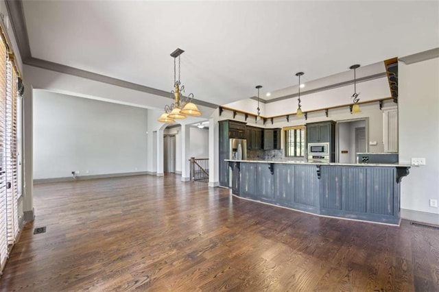 kitchen featuring stainless steel microwave, a kitchen breakfast bar, hanging light fixtures, tasteful backsplash, and kitchen peninsula