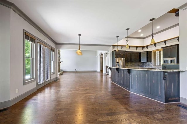 kitchen with appliances with stainless steel finishes, dark brown cabinets, a kitchen bar, and decorative light fixtures