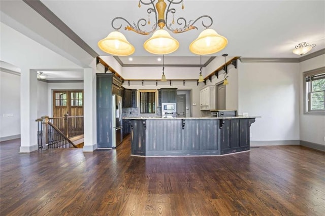 kitchen with a breakfast bar, crown molding, stainless steel fridge, built in microwave, and decorative light fixtures