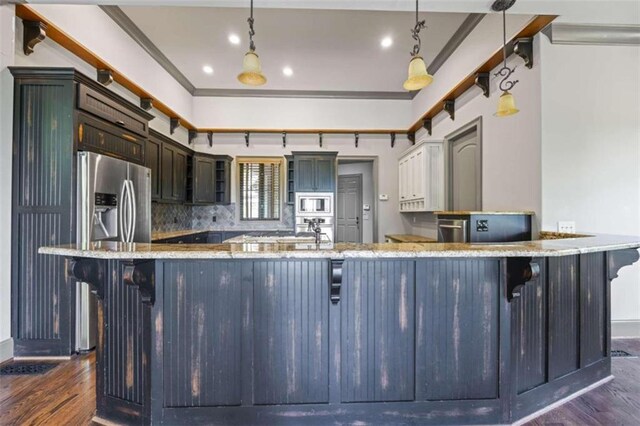 kitchen with backsplash, built in microwave, hanging light fixtures, and stainless steel refrigerator with ice dispenser