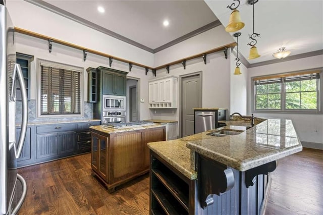 kitchen featuring light stone countertops, sink, stainless steel appliances, decorative light fixtures, and a kitchen island with sink