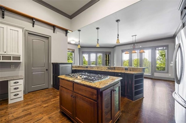 kitchen featuring decorative light fixtures, a kitchen island, ornamental molding, and appliances with stainless steel finishes