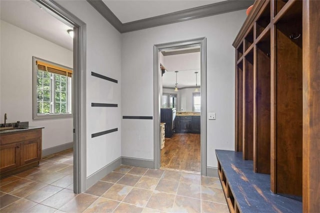 mudroom featuring plenty of natural light, crown molding, light tile patterned floors, and sink