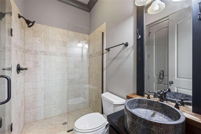 bathroom featuring a shower with shower door, toilet, ornamental molding, and sink