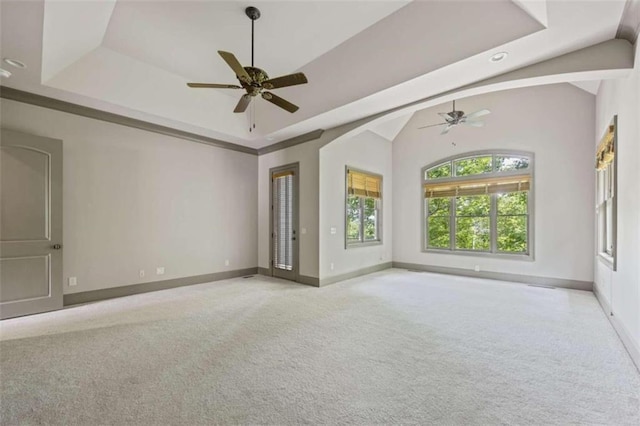 unfurnished room featuring ceiling fan, vaulted ceiling, light carpet, and a tray ceiling