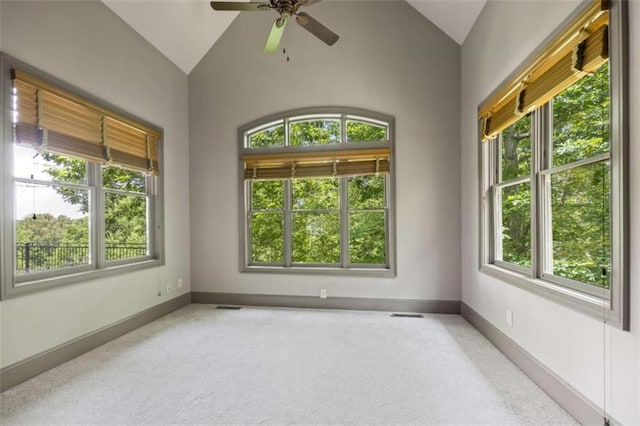 empty room featuring a wealth of natural light, ceiling fan, and vaulted ceiling