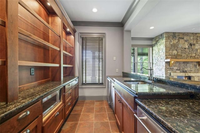 kitchen featuring appliances with stainless steel finishes, dark stone counters, crown molding, sink, and dark tile patterned flooring