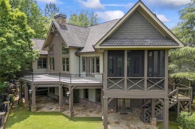 rear view of house with a wooden deck, a sunroom, a yard, and a patio