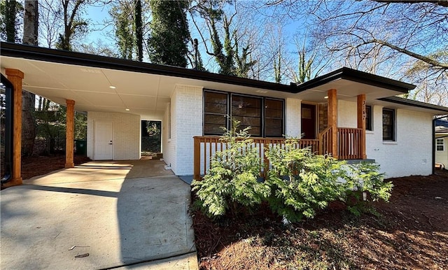 view of front of property featuring brick siding, an attached carport, and driveway