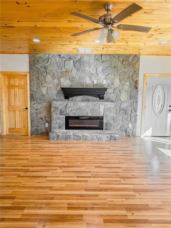 unfurnished living room featuring a stone fireplace, light hardwood / wood-style floors, and wooden ceiling