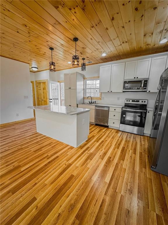 kitchen featuring appliances with stainless steel finishes, light hardwood / wood-style flooring, white cabinets, pendant lighting, and wooden ceiling