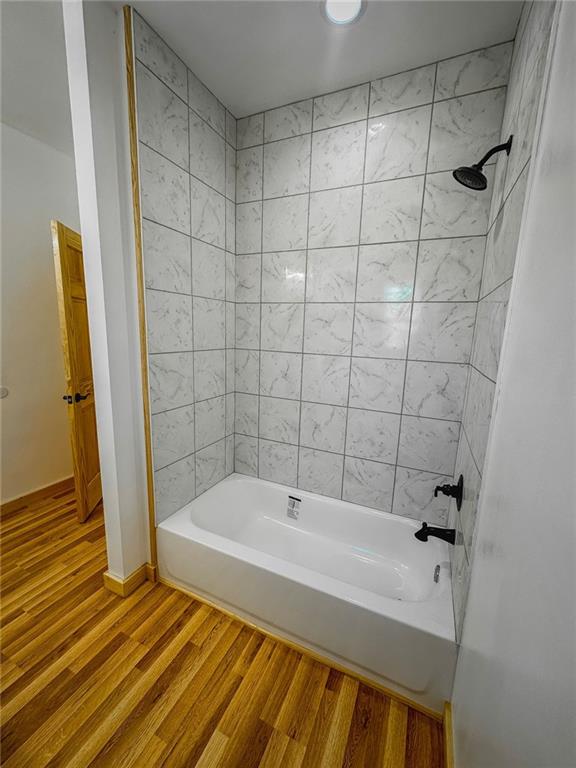 bathroom with hardwood / wood-style flooring and tiled shower / bath combo