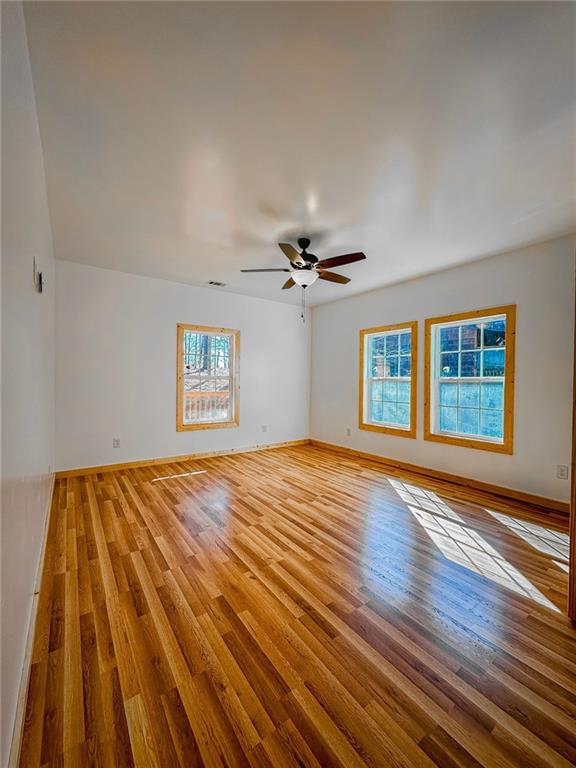 unfurnished room featuring plenty of natural light, ceiling fan, and wood-type flooring