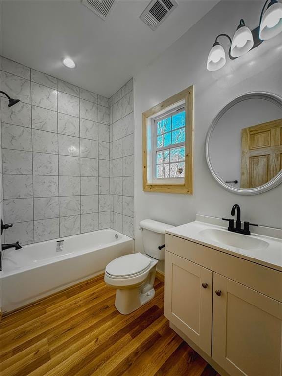 full bathroom featuring hardwood / wood-style floors, toilet, tiled shower / bath combo, and vanity