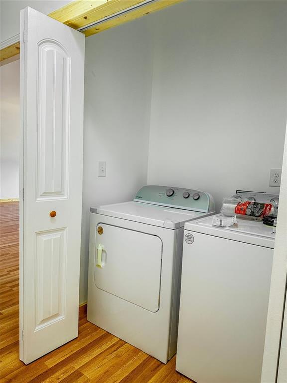 washroom with light hardwood / wood-style floors and separate washer and dryer