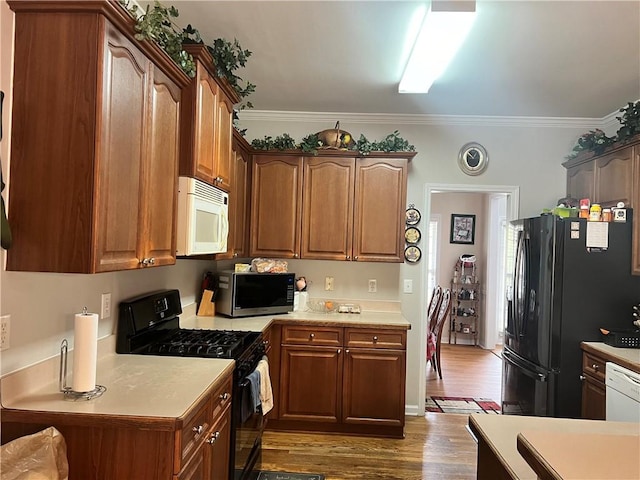 kitchen featuring black appliances, dark hardwood / wood-style flooring, and ornamental molding