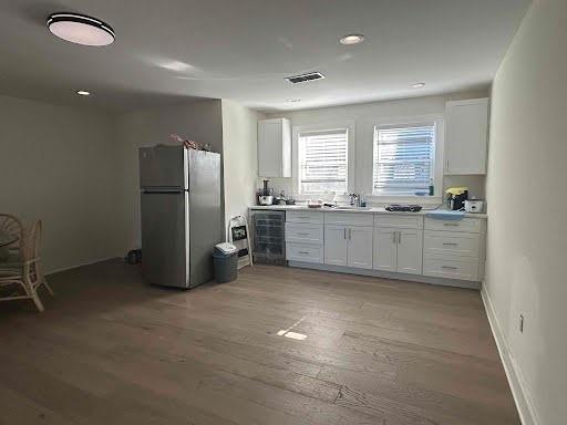 kitchen featuring light countertops, freestanding refrigerator, and white cabinets