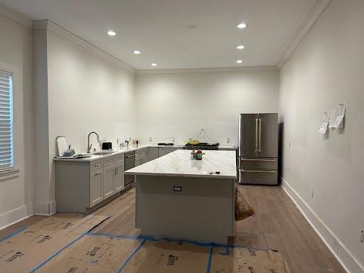 kitchen with light wood-style flooring, appliances with stainless steel finishes, and crown molding