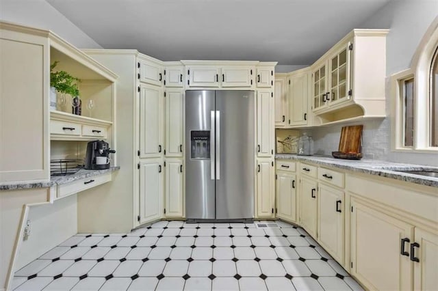 kitchen featuring stainless steel fridge with ice dispenser, backsplash, and cream cabinets