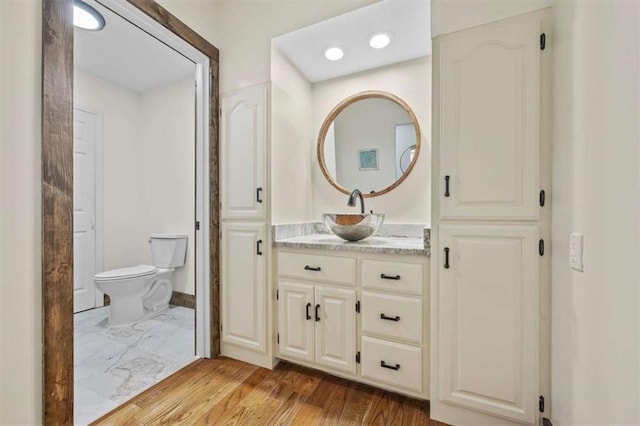 bathroom with hardwood / wood-style floors, toilet, and vanity