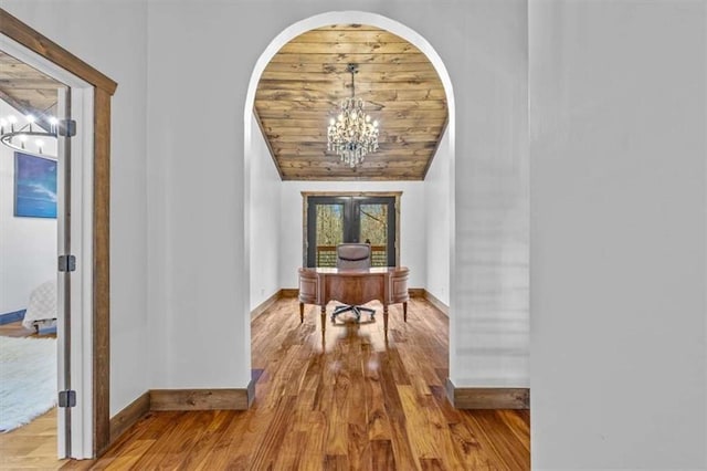 hall featuring lofted ceiling, wood ceiling, an inviting chandelier, and light hardwood / wood-style floors