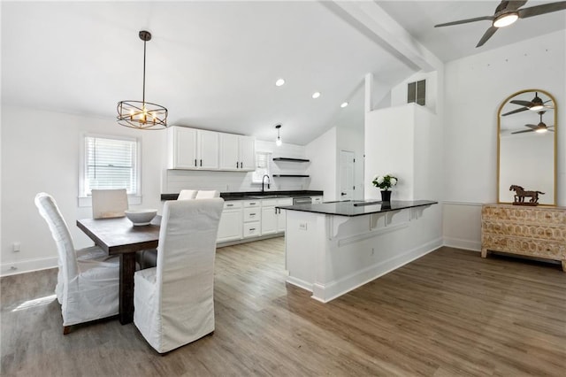 dining area featuring sink, hardwood / wood-style floors, high vaulted ceiling, ceiling fan with notable chandelier, and beamed ceiling