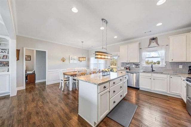 kitchen with white cabinetry, dark wood finished floors, ornamental molding, a sink, and stainless steel dishwasher