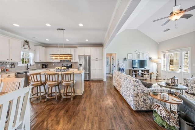 kitchen featuring visible vents, crown molding, vaulted ceiling, white cabinets, and stainless steel appliances