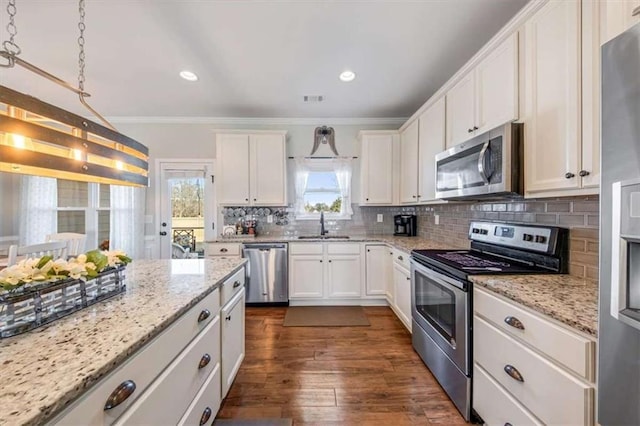 kitchen featuring visible vents, a sink, stainless steel appliances, crown molding, and tasteful backsplash