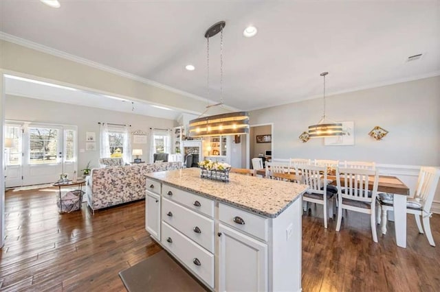 kitchen with dark wood-type flooring, white cabinets, a fireplace, and a center island