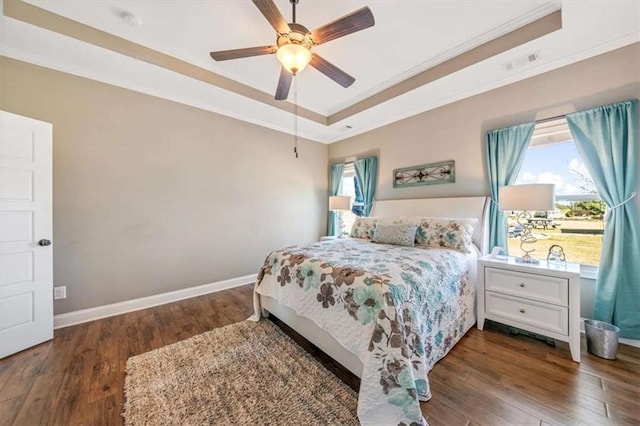 bedroom with visible vents, a raised ceiling, ornamental molding, hardwood / wood-style flooring, and baseboards