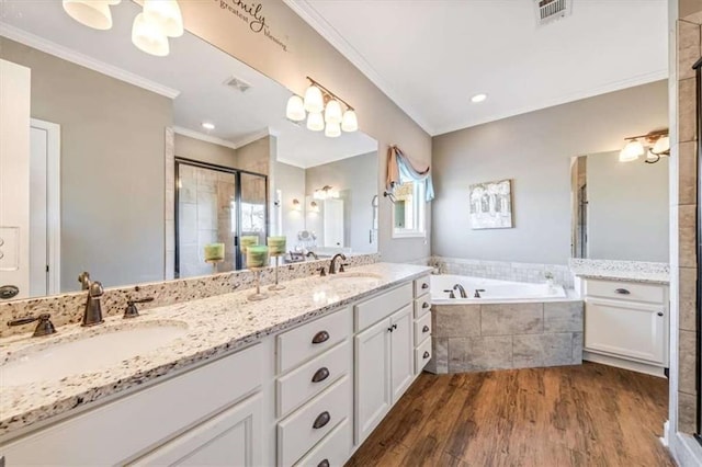 bathroom with wood finished floors, a stall shower, a sink, crown molding, and a bath