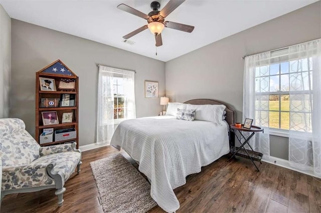 bedroom with ceiling fan, wood finished floors, visible vents, and baseboards