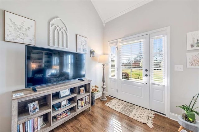 foyer with lofted ceiling, crown molding, wood finished floors, and baseboards