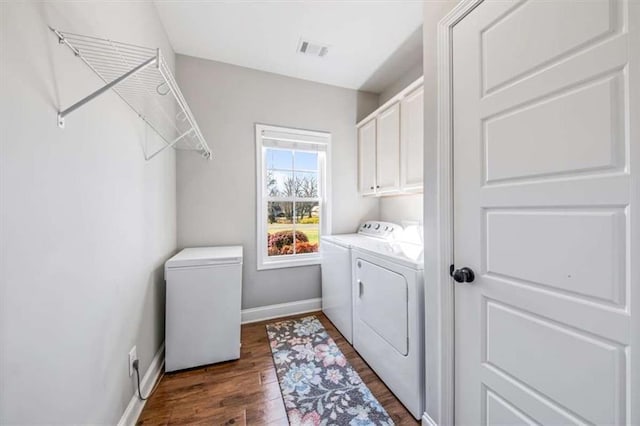 washroom featuring visible vents, dark wood-type flooring, baseboards, washing machine and dryer, and cabinet space