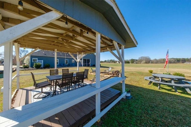 deck with outdoor dining space, a gazebo, and a lawn