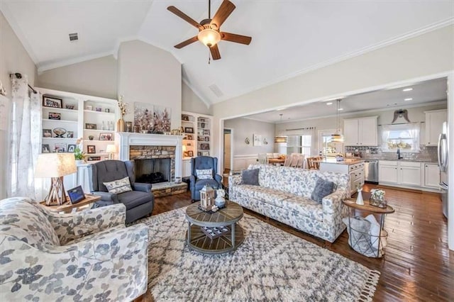 living area with visible vents, a fireplace, crown molding, and hardwood / wood-style floors