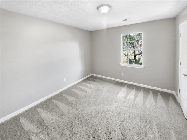 carpeted spare room featuring baseboards and visible vents