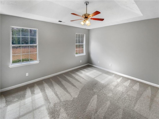 carpeted empty room featuring visible vents, ceiling fan, a wealth of natural light, and baseboards