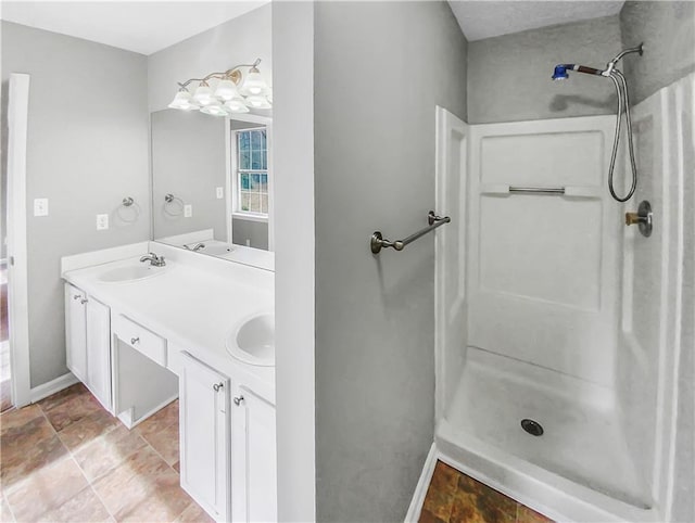 bathroom with double vanity, walk in shower, and a sink