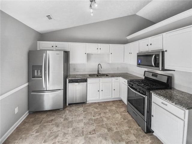 kitchen with lofted ceiling, white cabinetry, appliances with stainless steel finishes, and a sink