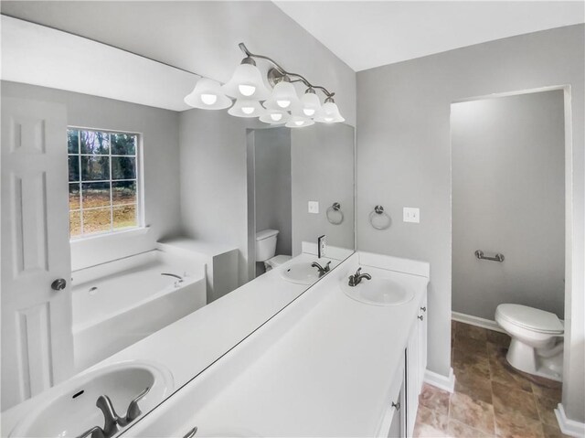 bathroom featuring double vanity, a sink, toilet, and baseboards