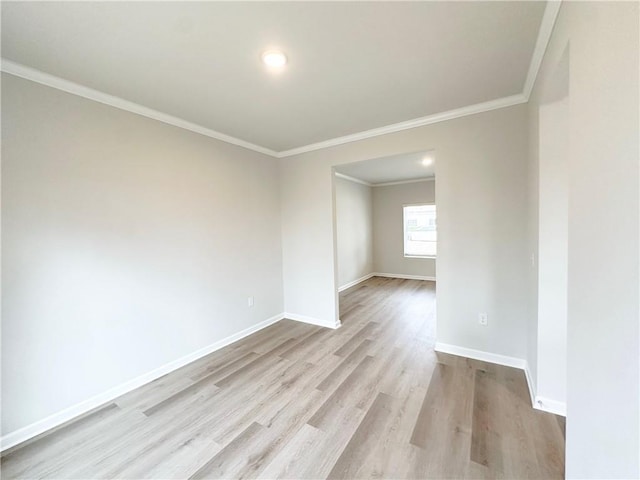 spare room with crown molding, wood finished floors, and baseboards