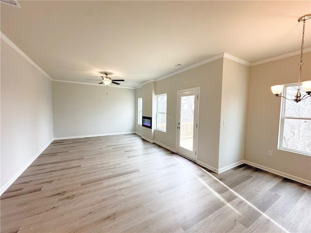 spare room with plenty of natural light, ceiling fan with notable chandelier, crown molding, and light wood-type flooring