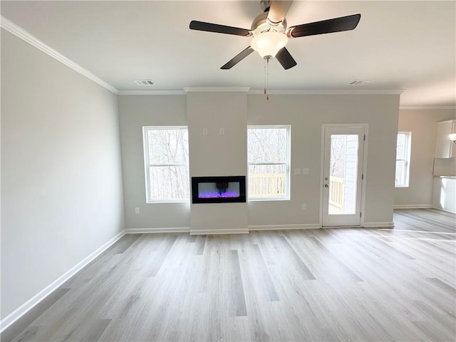 unfurnished living room featuring a wealth of natural light, a glass covered fireplace, light wood-type flooring, and crown molding