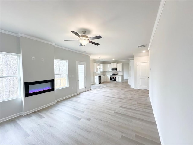 unfurnished living room with a ceiling fan, baseboards, ornamental molding, light wood-style floors, and a glass covered fireplace